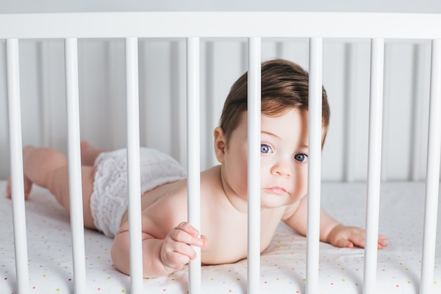 Kleine grappige jongen liggend in een babybed en lachen