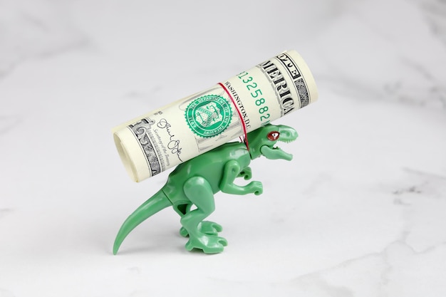 Kleine groene dinosaurus draagt roll dollar op zijn rug touw wurgt zijn nek