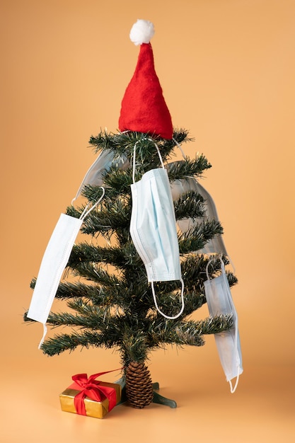 Kleine groene kerstboom versierd met kerstmuts en medische beschermende maskers