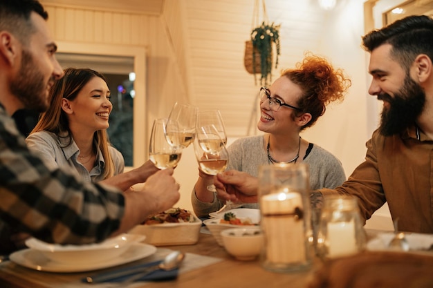 Kleine groep gelukkige vrienden die plezier hebben tijdens het roosteren tijdens het diner thuis Focus ligt op roodharige vrouw