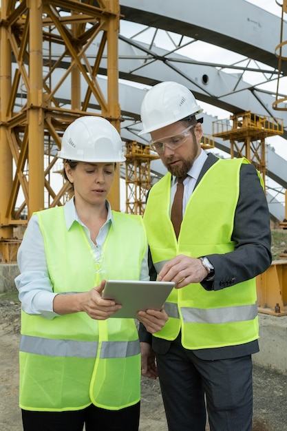 Kleine groep ingenieurs die door gegevens op het tabletscherm scrollen