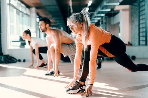 Kleine groep mensen met gezonde gewoonten doen rekoefeningen op een sportschool verdieping. selectieve aandacht op blonde vrouw. in achtergrondspiegel.