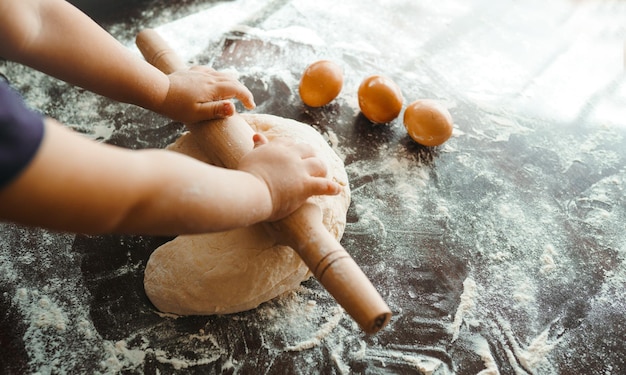 Kleine handen die deeg kneden Klein kind deeg voorbereiden om te bakken Kinderen geven wat meel