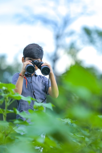 Kleine Indiase jongen geniet in de natuur met een verrekijker