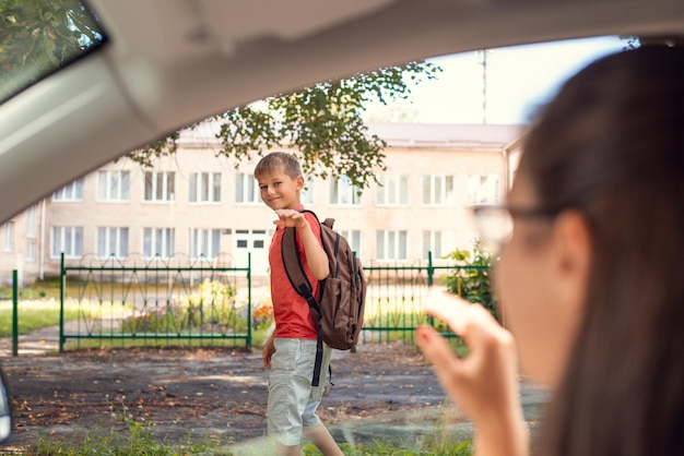 Kleine jongen basisschool leerling die naar school gaat en afscheid neemt van zijn moeder