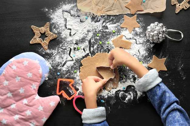 Kleine jongen bereidt kerstkoekjes aan tafel