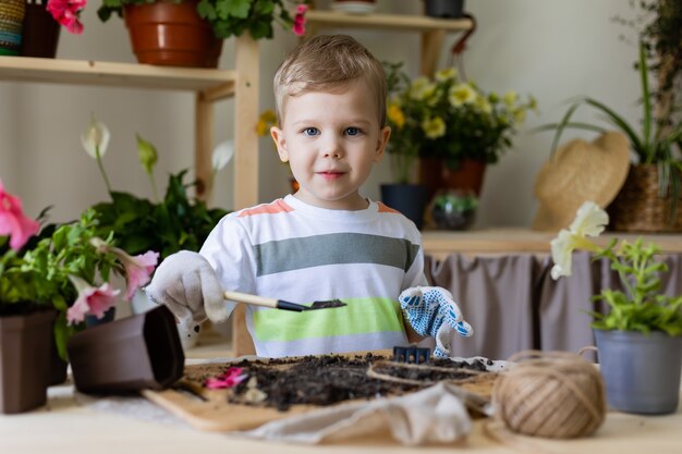 kleine jongen blond Europees uiterlijk planten of verplanten van huisplanten Kleine helper bij klusjes