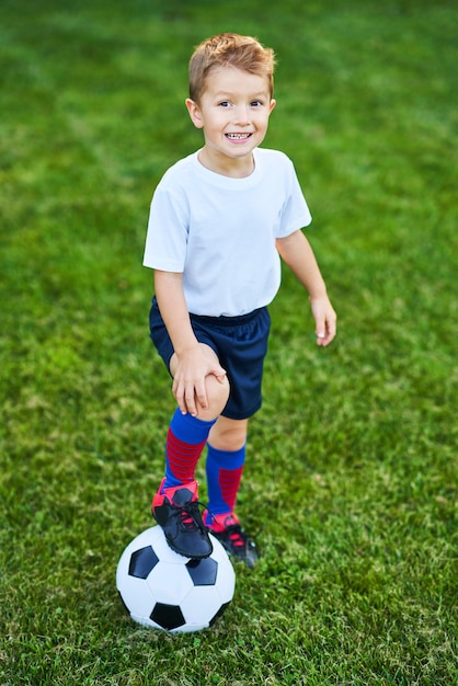 Kleine jongen buiten voetbal aan het oefenen