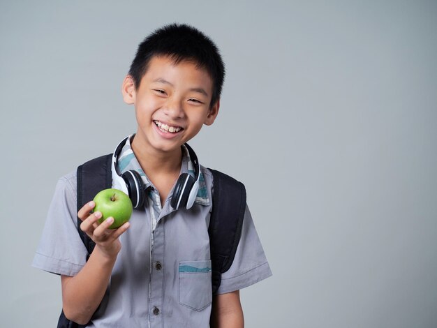 Kleine jongen die appel op grijze achtergrond houdt