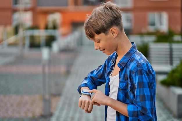 Kleine jongen die blauwe smartwatch buiten speelt.