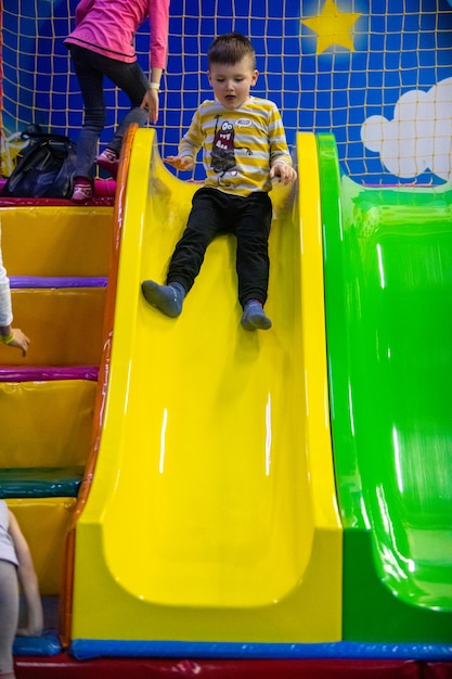 Kleine jongen die in het kleuterschoolpark glijdt