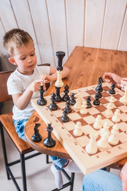 Kleine jongen die thuis aan tafel schaakt