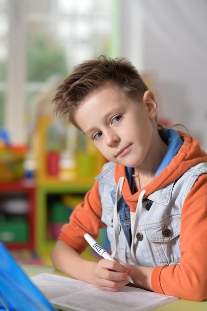 Kleine jongen die thuis lessen geeft in zijn kamer