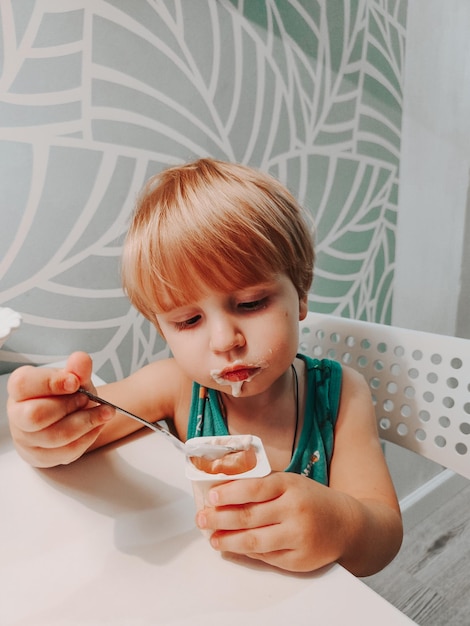 Foto kleine jongen die yoghurt eet in de keuken