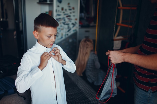 Kleine jongen dressing uniforme voorbereiding terug naar school.