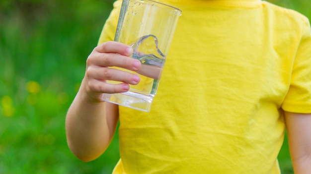 Kleine jongen drinkwater met een glas in het park