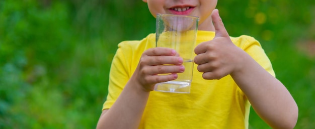 Kleine jongen drinkwater met een glas in het park