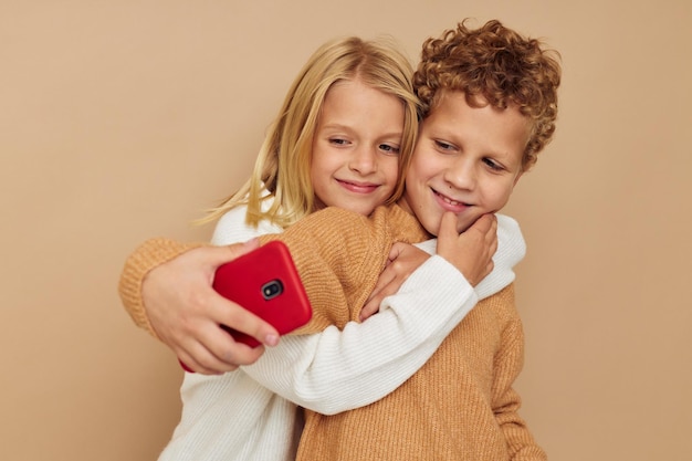 Kleine jongen en meisje met een rode telefoon samen technologieën geïsoleerde achtergrond