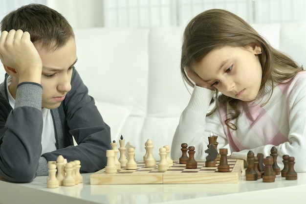 Kleine jongen en meisje schaken thuis. kinderen spelen schaken