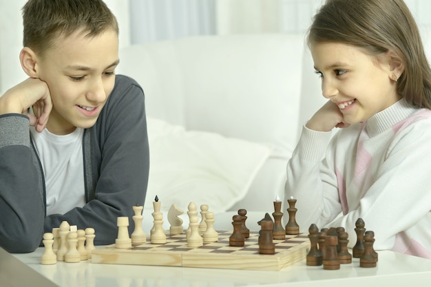 Kleine jongen en meisje schaken thuis. Kinderen spelen schaken