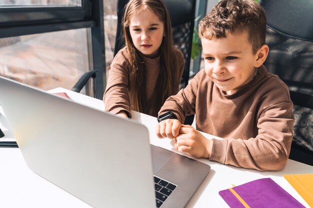 Kleine jongen en meisje studeren online thuis op de laptop