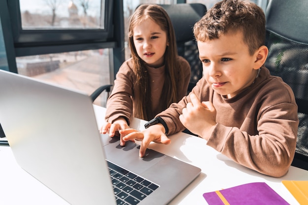 Kleine jongen en meisje studeren online thuis op de laptop
