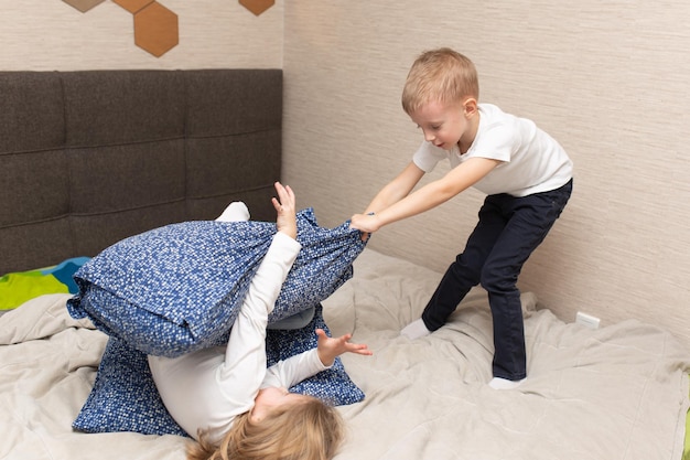 Foto kleine jongen en meisje voerden een kussengevecht op het bed in de slaapkamer ze houden van dat soort spel