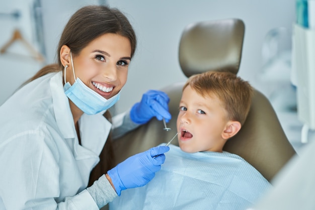 Kleine jongen en vrouwelijke tandarts in het tandartsenkantoor dentist