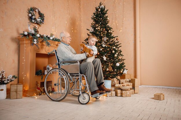 Kleine jongen en zijn oude grootvader in een rolstoel bij de kerstboom