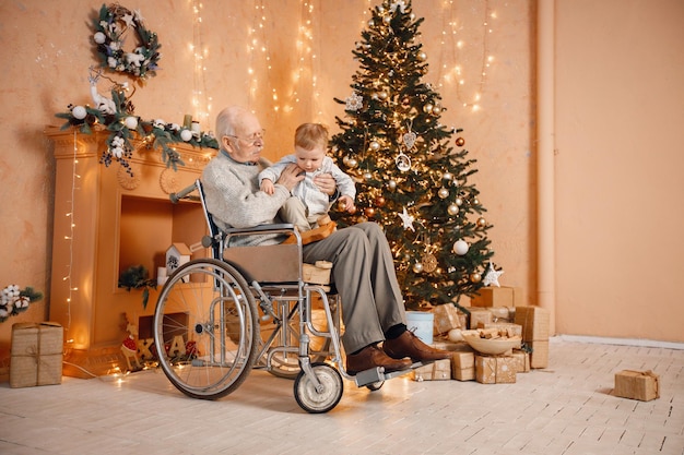 Kleine jongen en zijn oude grootvader in een rolstoel bij de kerstboom