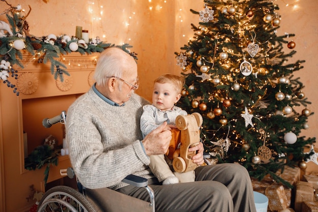 Kleine jongen en zijn oude grootvader in een rolstoel bij de kerstboom