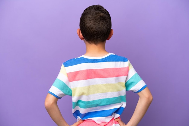 Kleine jongen geïsoleerd op paarse achtergrond in rugpositie