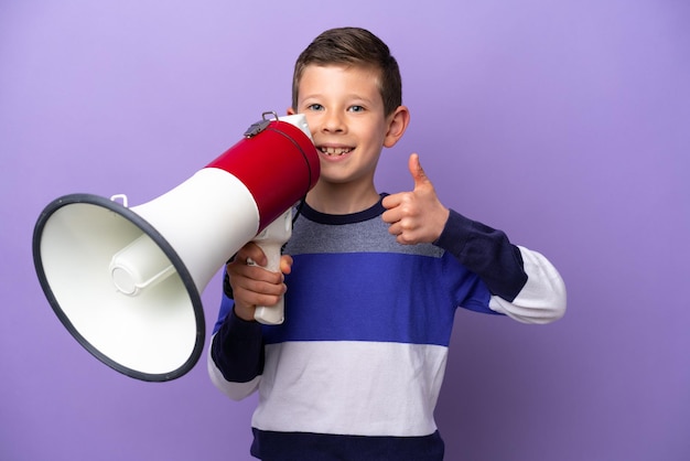 Kleine jongen geïsoleerd op paarse achtergrond met een megafoon met duim omhoog