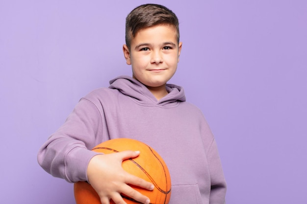 Kleine jongen gelukkige uitdrukking en houdt een basketbalbal
