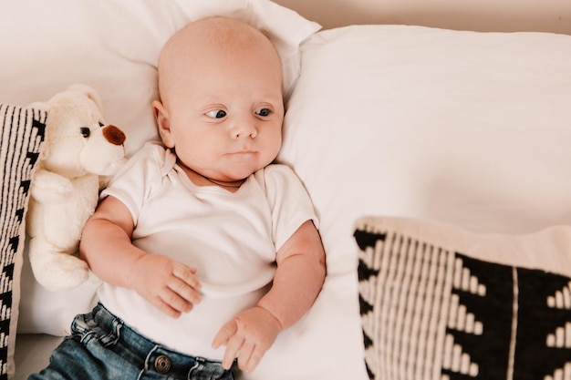 Kleine jongen grappig schattig kind baby liggend op bed kussens met pluizig speelgoed. Speelse peuter