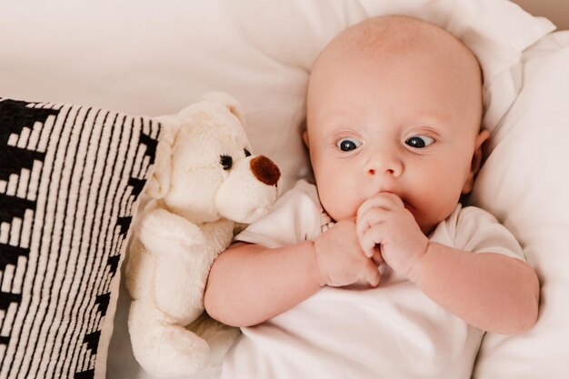 Kleine jongen grappig schattig kind baby liggend op bed kussens met pluizig speelgoed. Speelse peuter