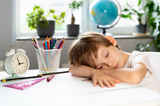 kleine jongen huiswerk thuis aan tafel, overwerk van een eersteklasser van studeren, stress