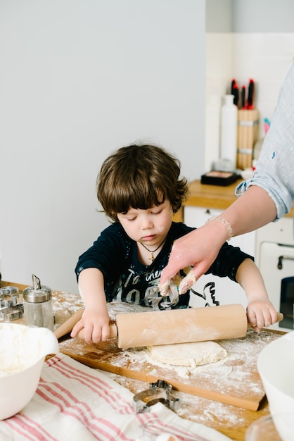 Kleine jongen in de keuken helpt bij het koken van het deeg voor het bakken