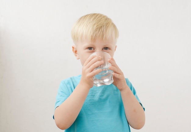 kleine jongen in een blauw T-shirt drinkt water