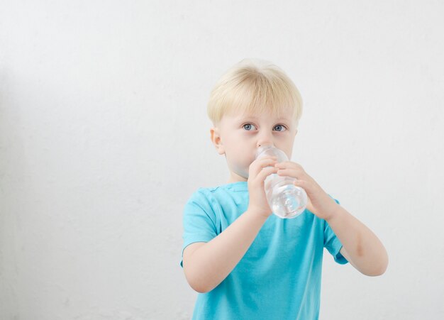 kleine jongen in een blauw T-shirt drinkt water