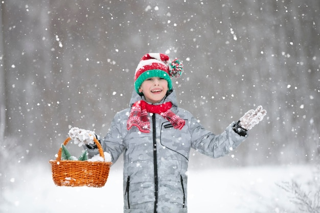 Kleine jongen in een gestreepte kerstmuts onder de sneeuw