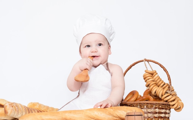 Kleine jongen in een koksmuts en met brood grappige kleine chef