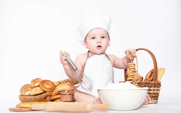 Kleine jongen in een koksmuts en met brood grappige kleine chef