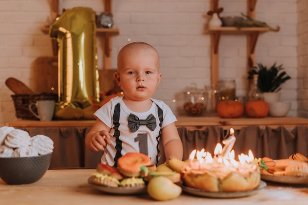 Kleine jongen in een T-shirt met nummer één strekt zijn hand uit naar de snoepjes op tafel. eerste verjaardag. gezonde zelfgemaakte zoetigheden. marshmallows, peperkoek, appeltaart, charlotte. Hoge kwaliteit foto