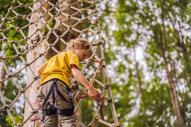 Kleine jongen in een touwpark Actieve fysieke recreatie van het kind in de frisse lucht in het park Training voor kinderen