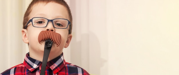 Kleine jongen in glazen met een decoratieve snor. nep snor. spel van het volwassen leven