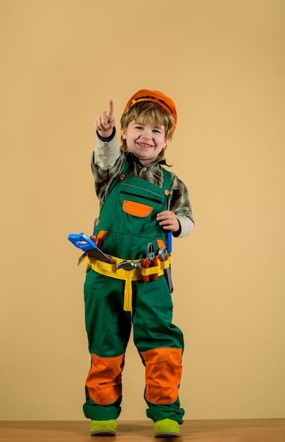 Kleine jongen in helm en gereedschap kind als bouwvakker kleine jongen in bouwersuniform met gereedschap