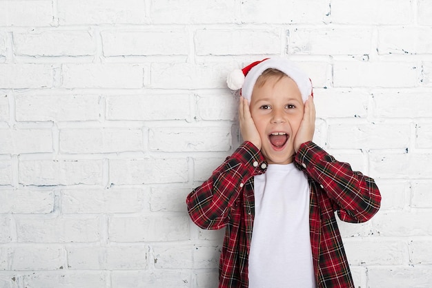 Kleine jongen in kerstmuts met peperkoekhuis op witte achtergrond Gelukkig nieuwjaarskaart Wachten op de vakantie