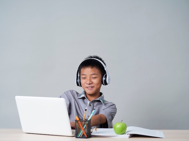 Kleine jongen in koptelefoon studeren online met behulp van laptop