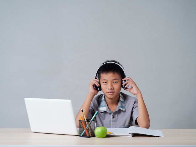 Kleine jongen in koptelefoon studeren online met behulp van laptop